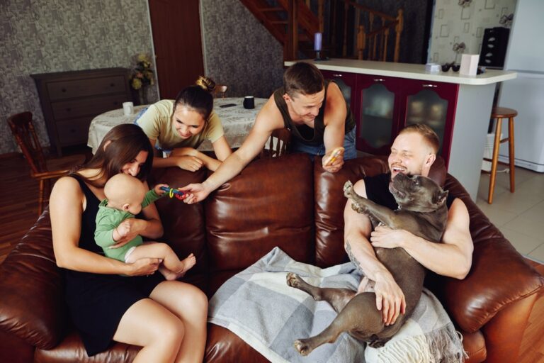 Young family sitting on a sofa with their Micro American Bully dog and baby girl in the living room